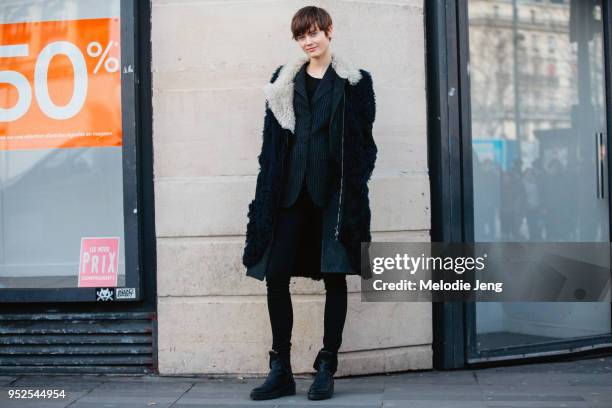 Model Jac Jagaciak wears a black teddy bear shearling coat, a black pinstripe blazer, black pants, and black boots on March 05, 2018 in Paris, France.