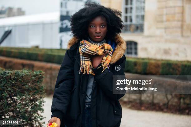 Model Assa Baradji wears a yellow Burberry tartan scarf and black Ted Lapidus anorak after the Dior show on March 27, 2018 in Paris, France.