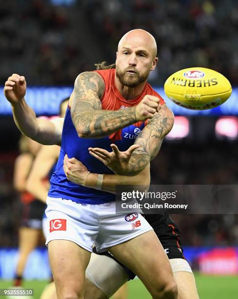 Nathan Jones of the Demons handballs whilst being tackled during the round 6 AFL match between the Essendon Bombers and Melbourne Demons at Etihad...