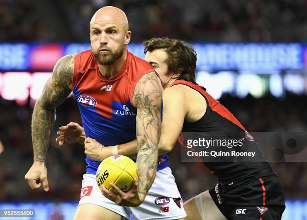 Nathan Jones of the Demons handballs whilst being tackled during the round 6 AFL match between the Essendon Bombers and Melbourne Demons at Etihad...