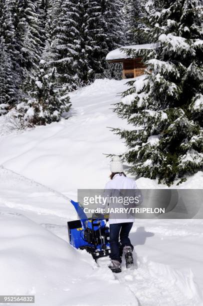 Haute-Savoie Massif des Aravis, station de ski et village Le Grand Bornand, vallée du Bouchet, personne déneigeant avec une fraise à neige.