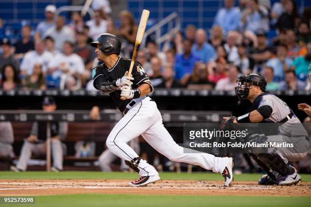 Martin Prado of the Miami Marlins hits an hits an RBI single to score J.T. Realmuto during the first inning of the game against the Colorado Rockies...