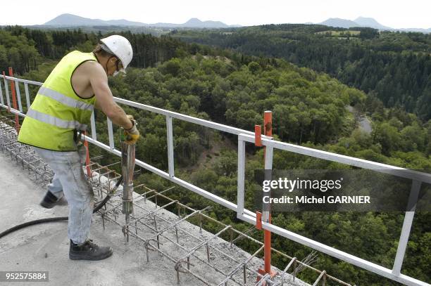 Chantier de construction de l'autoroute A89 sur le reseau d'Autoroute du Sud de la France . Ouvrier preparant au marteau-piqueur la pose du parapet...