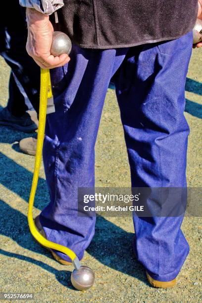 Joueur de pétanque ramassant une boule avec un aimant, 16 Mars 2017, Sarthe, France.