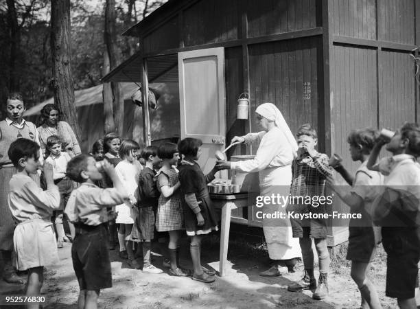 Une cuisinière sert des rafraîchissements à des écoliers lors d'une classe en plein air au bois de Vincennes à Paris, France.