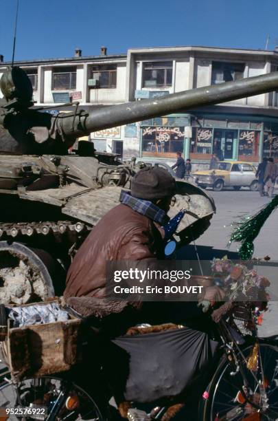 Un homme tire sa bicyclette chargée devant un char d'assaut de l'armée soviétique, le 10 février 1989, à Kaboul, Afghanistan.