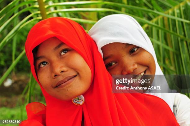 Two smiling girl looking up with colorful veil, Banda Aceh, Sumatra, Indonesia.