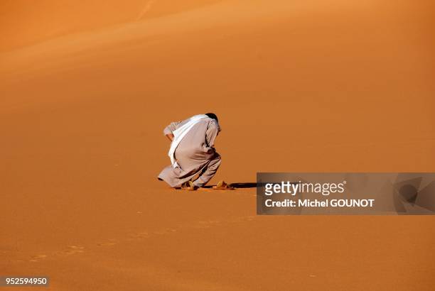 Devot musulman faisant sa priere dans le desert.