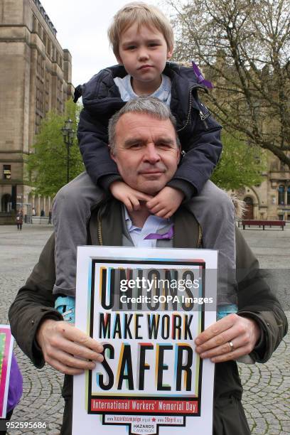 Father carries his young son on his shoulders whilst his sign reads "Unions make Work Safer" at the International Workers Memoriial Day rally in...