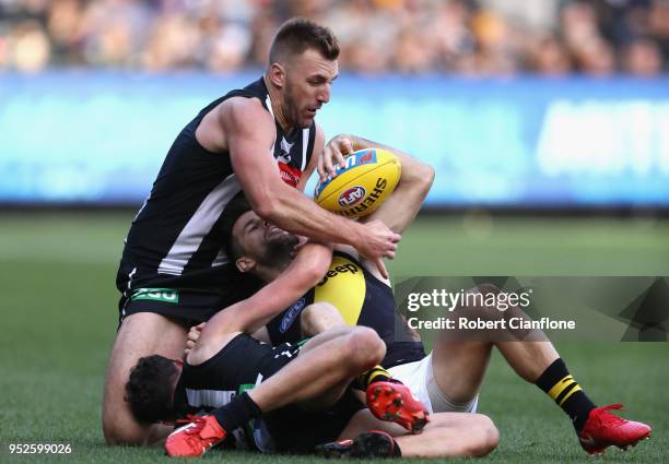 Trent Cotchin of the Tigers is challenged by Lynden Dunn and Flynn Appleby of the Magpies during the AFL round six match between the Collingwood...