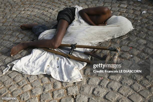 Crippled Ethiopian beggar has covered his head with his white robe and is sleeping in the street near a church, 2009 in Bahir Dar, Ethiopia.