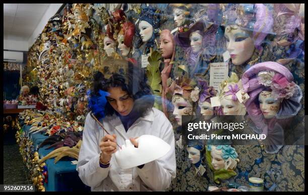 Une femme peint le masque dans une boutique de déguisement, Venise, Italie.