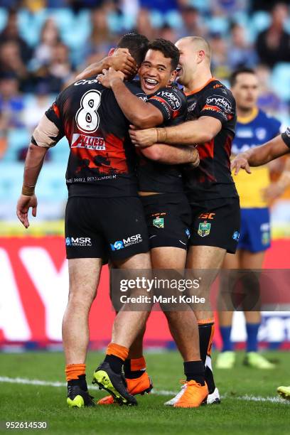 Matt Eisenhuth, Esan Marsters and Robbie Rochow of the Tigers celebrate Matt Eisenhuth scoring a try during the round Eight NRL match between the...