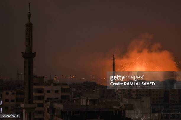 Picture taken late on April 28, 2018 shows explosions appearing in the skyline of a southern district of the Syrian capital Damascus, during regime...