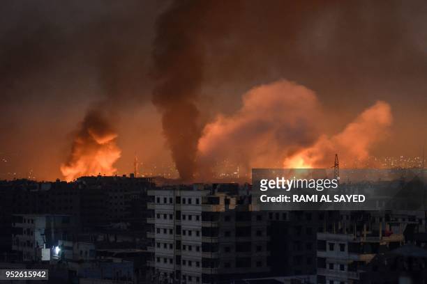 Picture taken late on April 28, 2018 shows smoke plumes rising from explosions in the skyline of a southern district of the Syrian capital Damascus,...