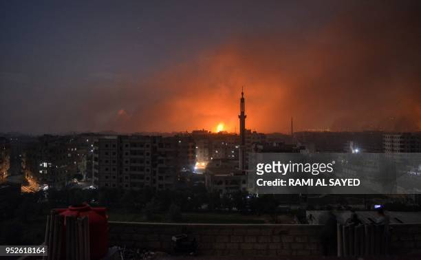 Picture taken late on April 28, 2018 shows explosions appearing in the skyline of a southern district of the Syrian capital Damascus, during regime...
