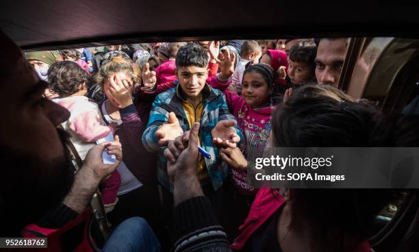 Children reach out to Kurdish Red Crescent aid workers distributing milk, outside of Tall Rifat. An estimated 400,000 refugees fleeing the...