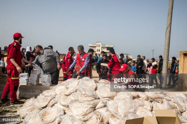 Crowd of refugees displaced from Efrin gather around a Syrian Arab Red Crescent worker to register for aid in the town of Tall Rifat. An estimated...