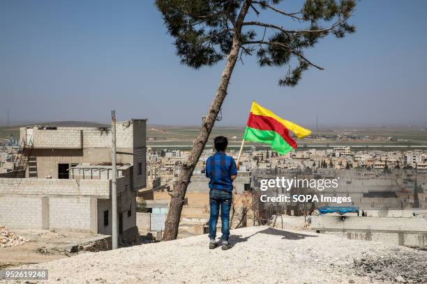 Boy seen standing on a hill in kobani and raising a Kurdish flag toward the Turkish flag on the other side. An estimated 400,000 refugees fleeing the...