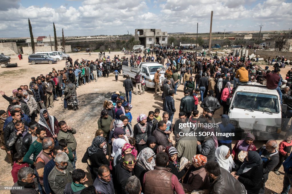 Thousands of people displaced from Afrin line up to receive...