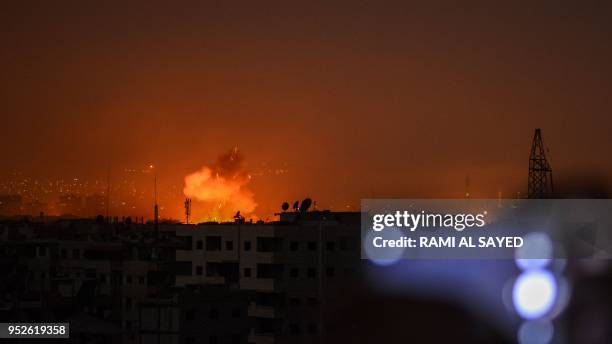 Picture taken late on April 28, 2018 shows explosions appearing in the skyline of a southern district of the Syrian capital Damascus, during regime...