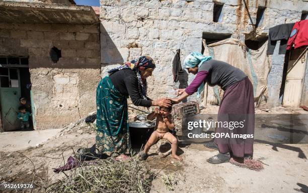 Family displaced from Afrin living in the corner of a destroyed house in Fafin. They cook and take a shower outside their new destroyed home. An...