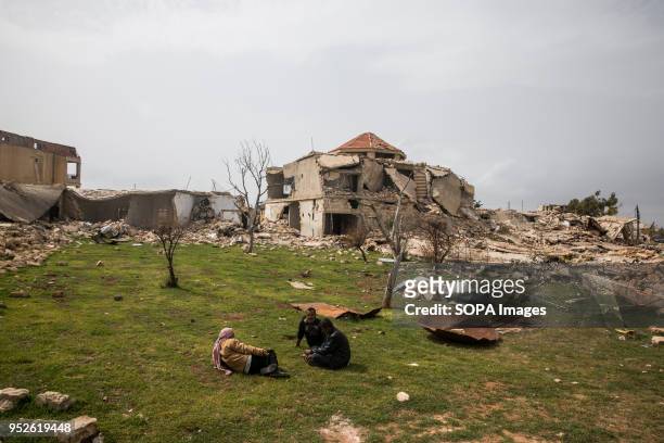 Men sit in the backyard of an empty home they resettled after being displaced by the conflict in Afrin. An estimated 400,000 refugees fleeing the...