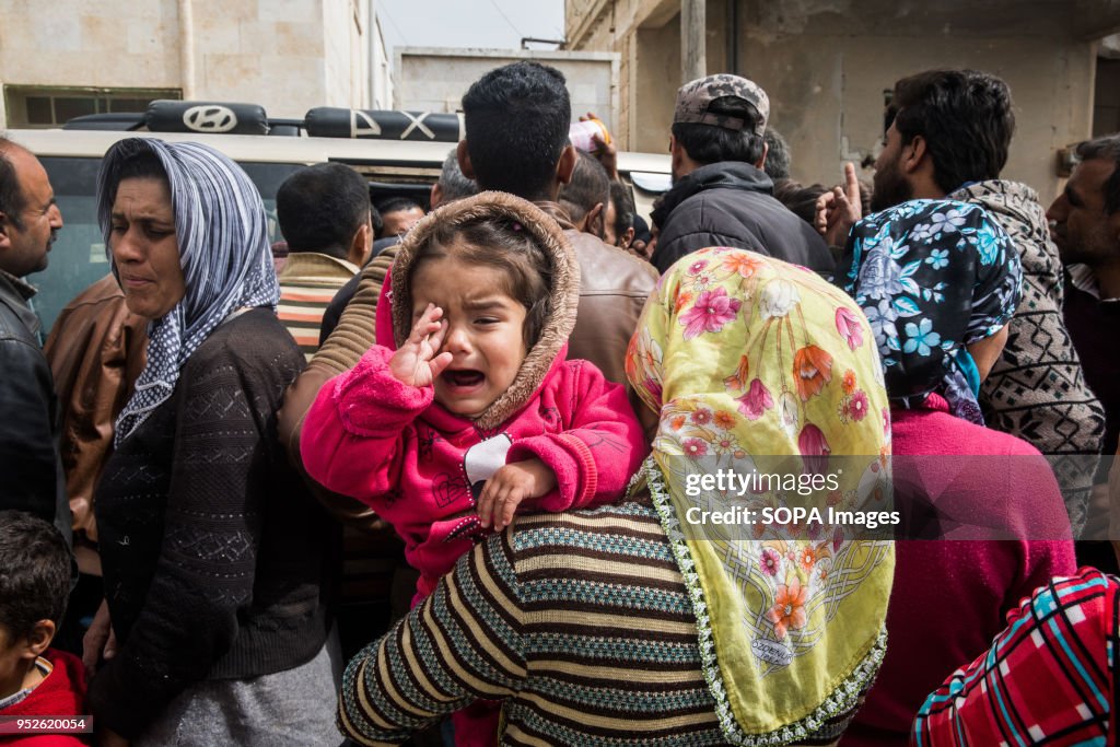 A child cries out as her mother waits to receive aid from...