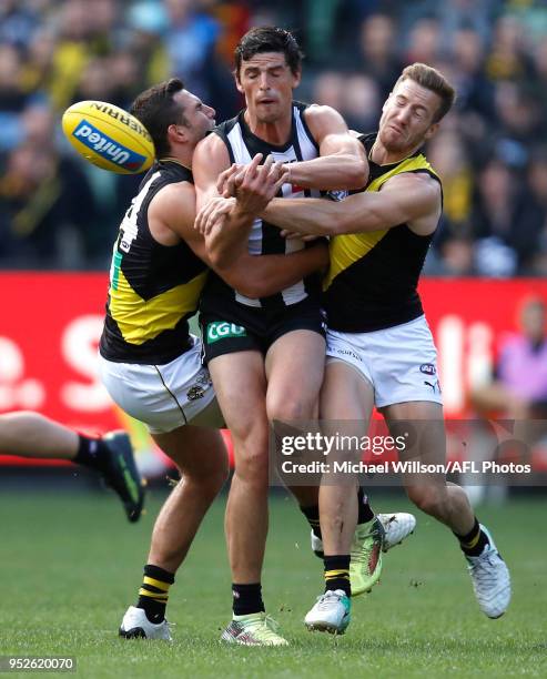 Scott Pendlebury of the Magpies is tackled by Jack Graham and Kane Lambert of the Tigers during the 2018 AFL round six match between the Collingwood...