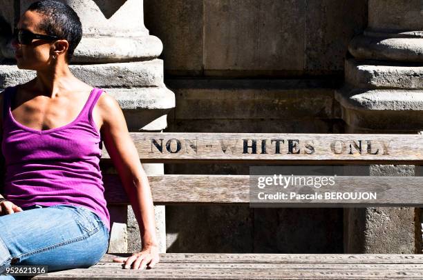 Jeune femme métissée, assise sur un banc marquant la segrégation raciale du regime de l'apartheid, situé devant la Haute Cour a Cape Town, 12 mars...