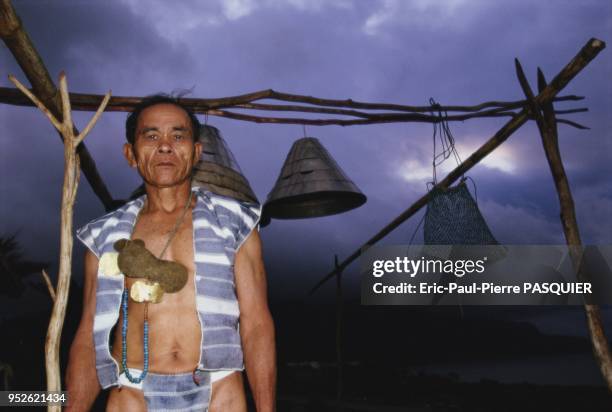 The Yami People Of Lanyu. Yami posing next to the silver helmets which are hung after returning from the fishing expedition.
