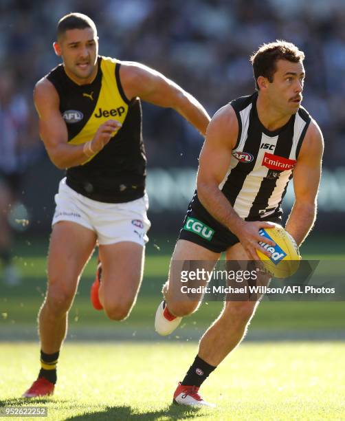 Jarryd Blair of the Magpies is chased by Shaun Grigg of the Tigers during the 2018 AFL round six match between the Collingwood Magpies and the...