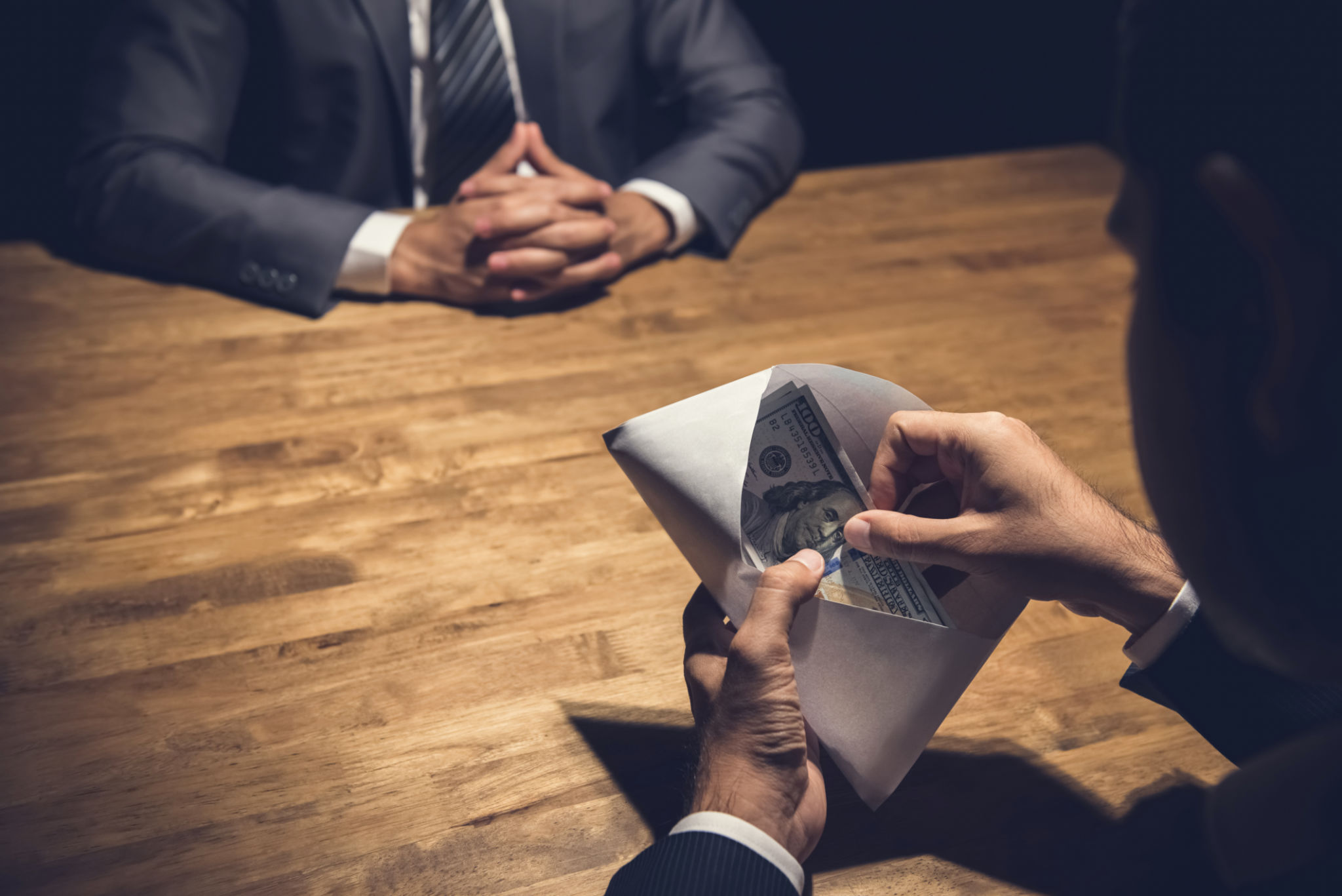Businessman checking money, US dollars, in the envelope just given by his partner Businessman checking money, US dollars, in the envelope just given by his partner