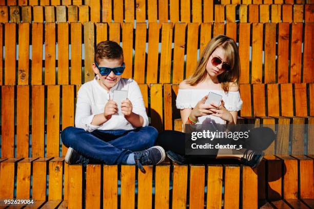 jungen und mädchen im freien zu sitzen und mit handy - familie banner stock-fotos und bilder