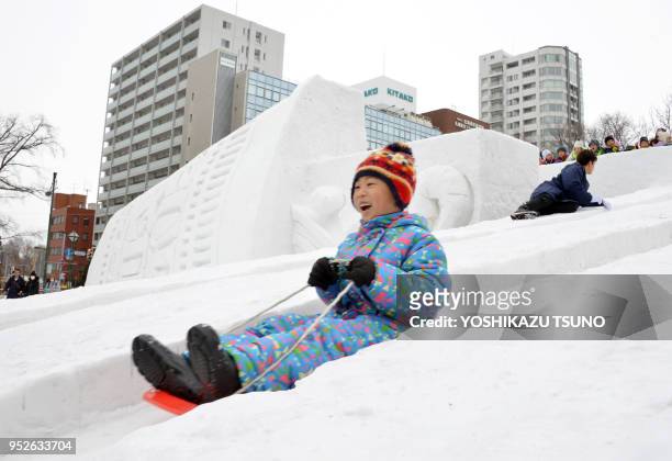 Boy plays on a snow slide at the annual Sapporo Snow Festival in Sapporo in Japan's nortern island of Hokkaido on February 6, 2017. The week-long...