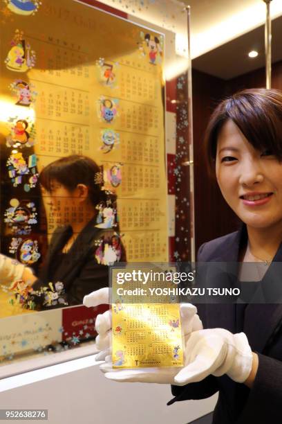 Une employée de la bijouterie japonaise Tanaka Kikinzoku présente au public un calendrier avec des peersonnages Disney en or massif de 12,5 kg, sa...