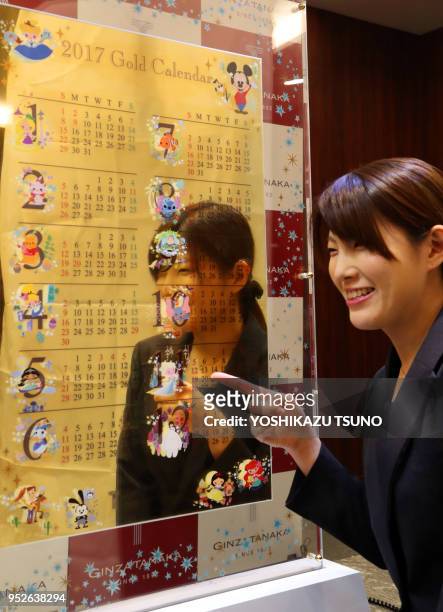 Une employée de la bijouterie japonaise Tanaka Kikinzoku présente au public un calendrier avec des peersonnages Disney en or massif de 12,5 kg, sa...