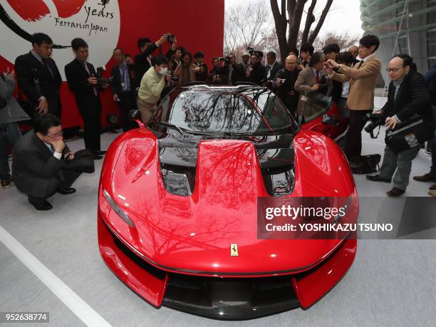 Japanese journalists admire Italian sports car maker Ferrari's new vehicle "Ferrari J50" at the world premiere in Tokyo on December 13, 2016 to...