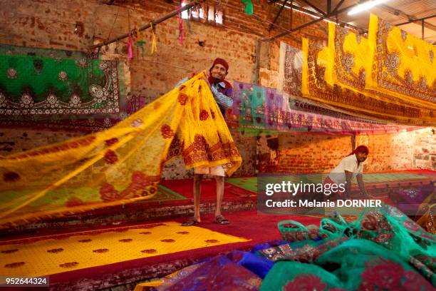 Travailleur pliant des saris qu'il vient de sérigraphier avec de la poudre de couleur rouge brillante, le 2 décembre 2014 à Sanganer près de Jaipur,...