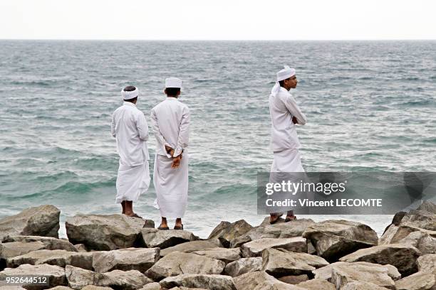 Trois jeunes hommes musulmans en tenue traditionnelle regardant l?Océan Indien à Varkala, dans l'état du Kerala, en Inde, le 10 février 2012.