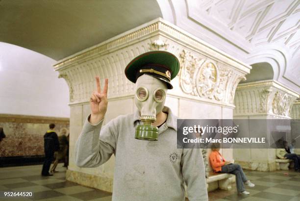 Un homme faisant le V de victoire avec un masque à gaz et une casquette de l'armée, station de métro Prospect Mira Moscou, Russie.