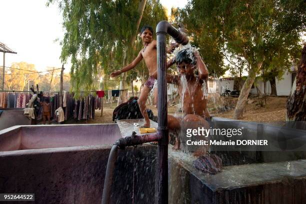Deux garcons se douchant au robinet d'un bac de rinçage profitant de l'eau chaude de l'atelier, le 2 décembre 2014 à Sanganer près de Jaipur,...