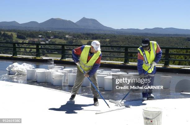 Mise en oeuvre d'une couche d'etancheite sur le tablier du viaduc de la Sioule, sur fond de chaine des Puys, lors de la construction de l'autoroute...