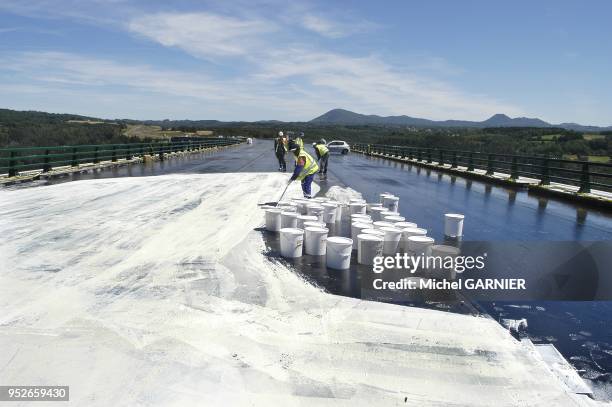 Mise en oeuvre d'une couche d'etancheite sur le tablier du viaduc de la Sioule, sur fond de chaine des Puys, lors de la construction de l'autoroute...