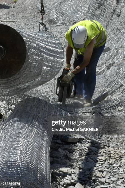 Securisation d'un talus rocheux a l'aide de grillage, par rapport aux chutes de pierres, sur un chantier de travaux publics, lors de la construction...