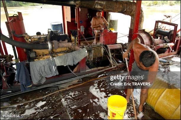 The chief engineer checks the suction device on a gold suction dredge operating on the Maroni river.