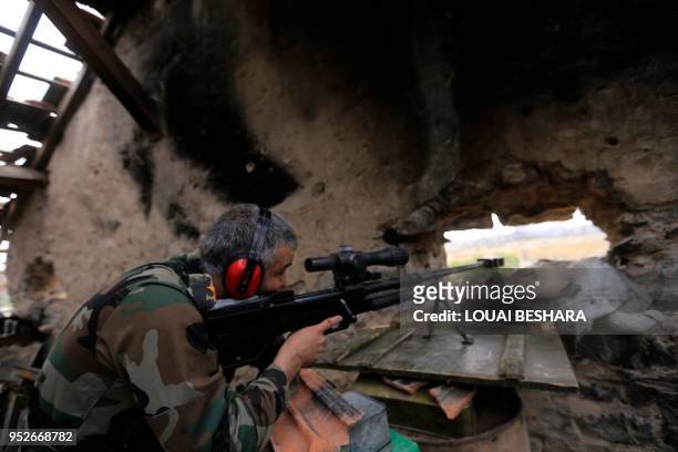 Picture taken on April 29 during a government guided tour in Damascus' southern al-Qadam neighbourhood, shows Syrian army sniper taking aim at...