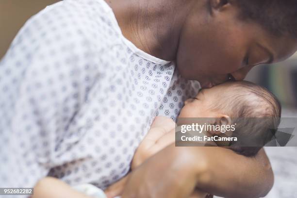 nouvelle maman tient son bébé sur sa poitrine - black mom photos et images de collection