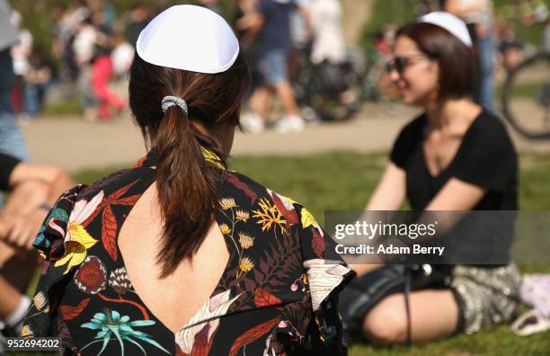 Visitors wear kippahs, or yarmulkes, handed out to them by volunteers in the Mauerpark public park during a day of demonstrations against...