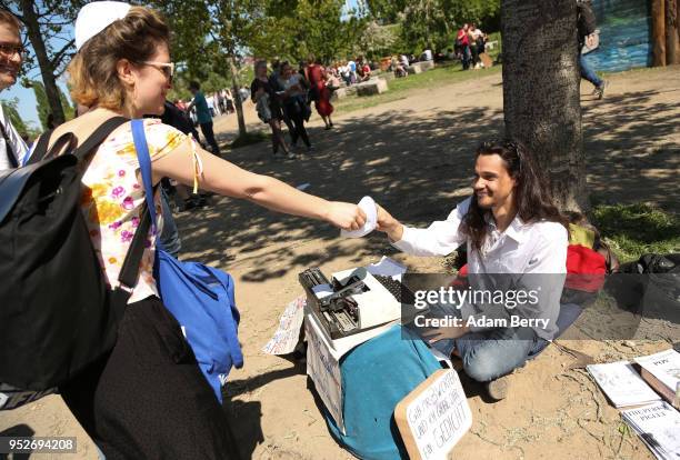 Volunteer hands out a kippah, or yarmulke, to a man selling poems in the Mauerpark public park during a day of demonstrations against antisemitism on...